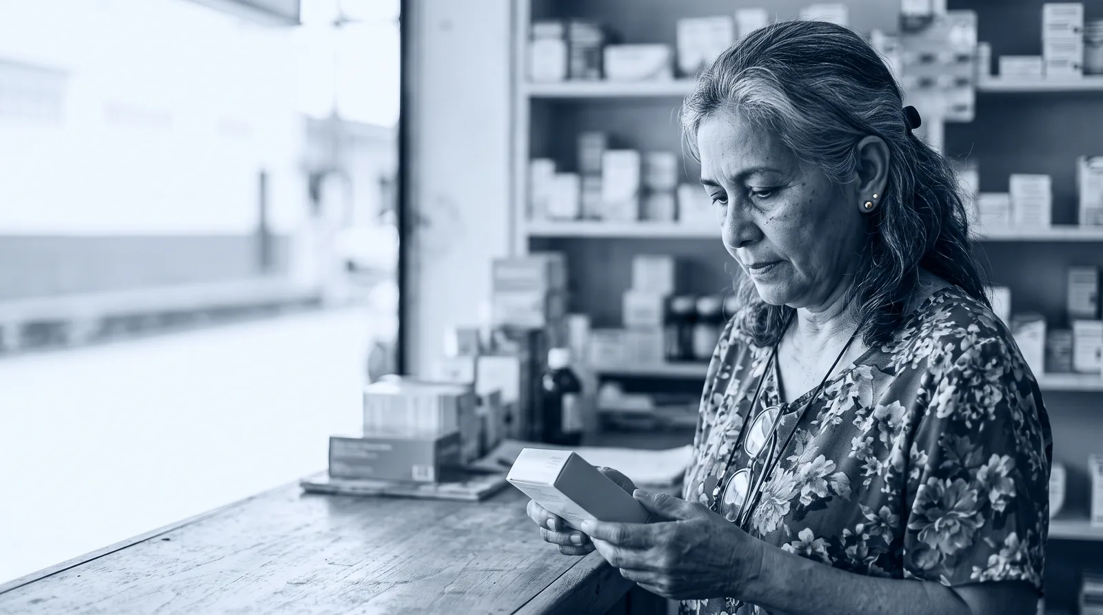 Una jubilada revisa el precio de un medicamento en el mostrador de una farmacia.